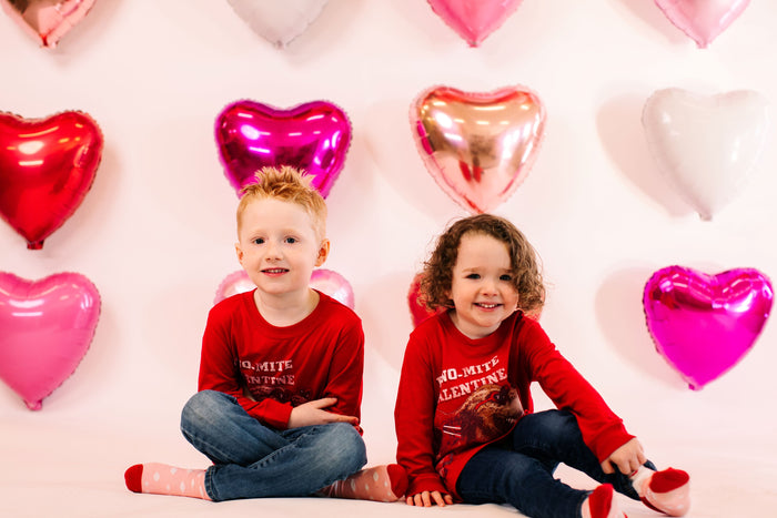 two children in front of heart foil balloons