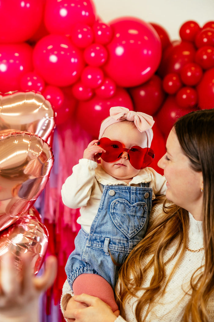 mother holding child with heart sunglasses