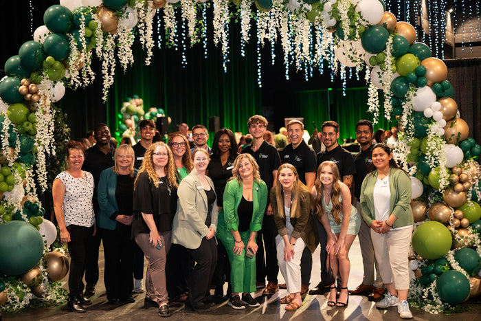 green and gold balloon archway install with florals