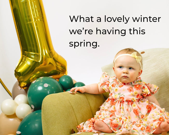 A young baby girl beside a balloon backdrop