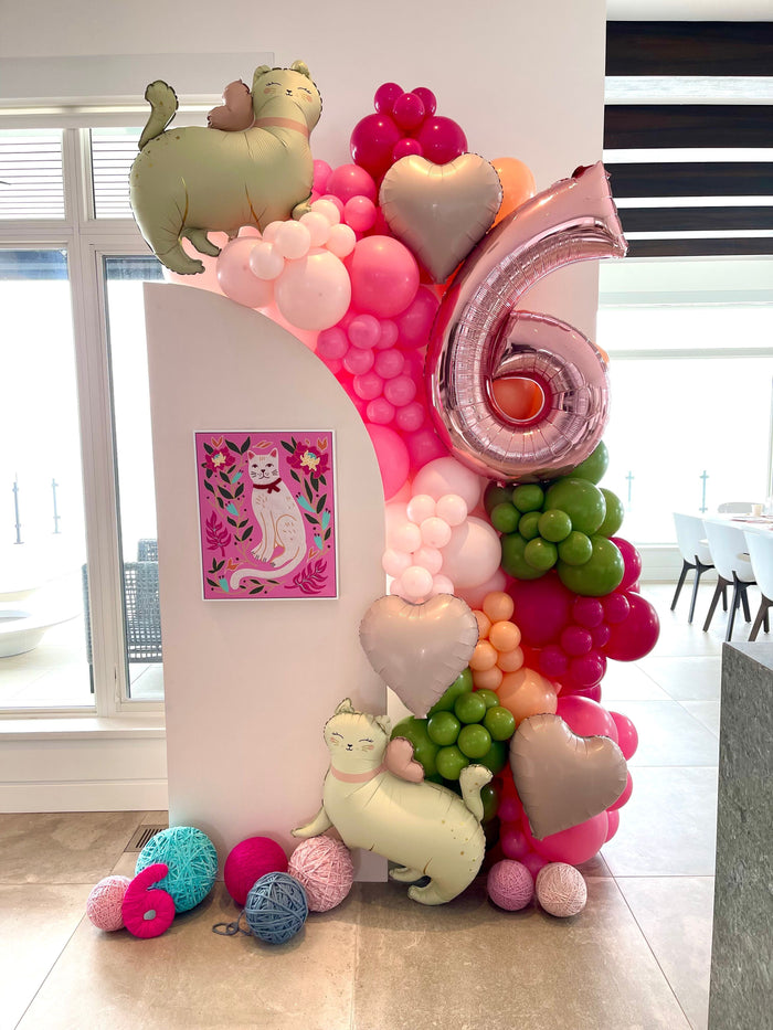 Pink and green balloon photo op with cat-themed accents create a photo op for a client's private party