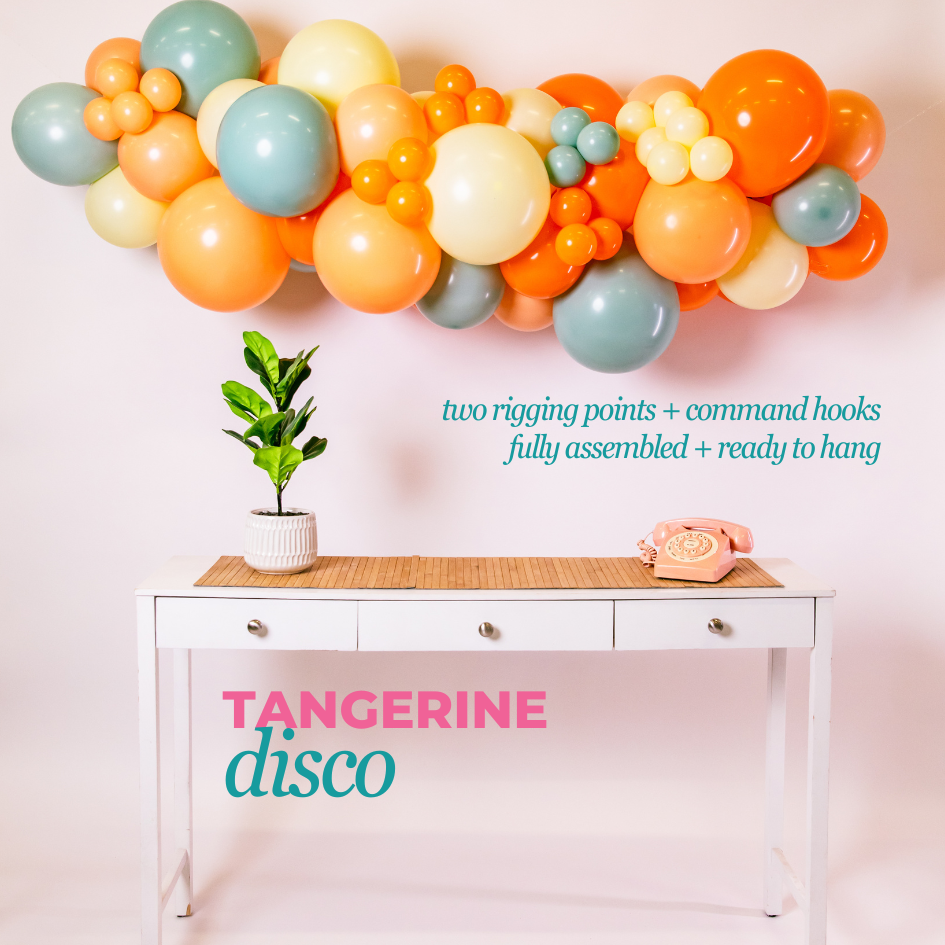 Colorful balloon arch above a table with a plant and phone, featuring 'Tangerine Disco' branding.